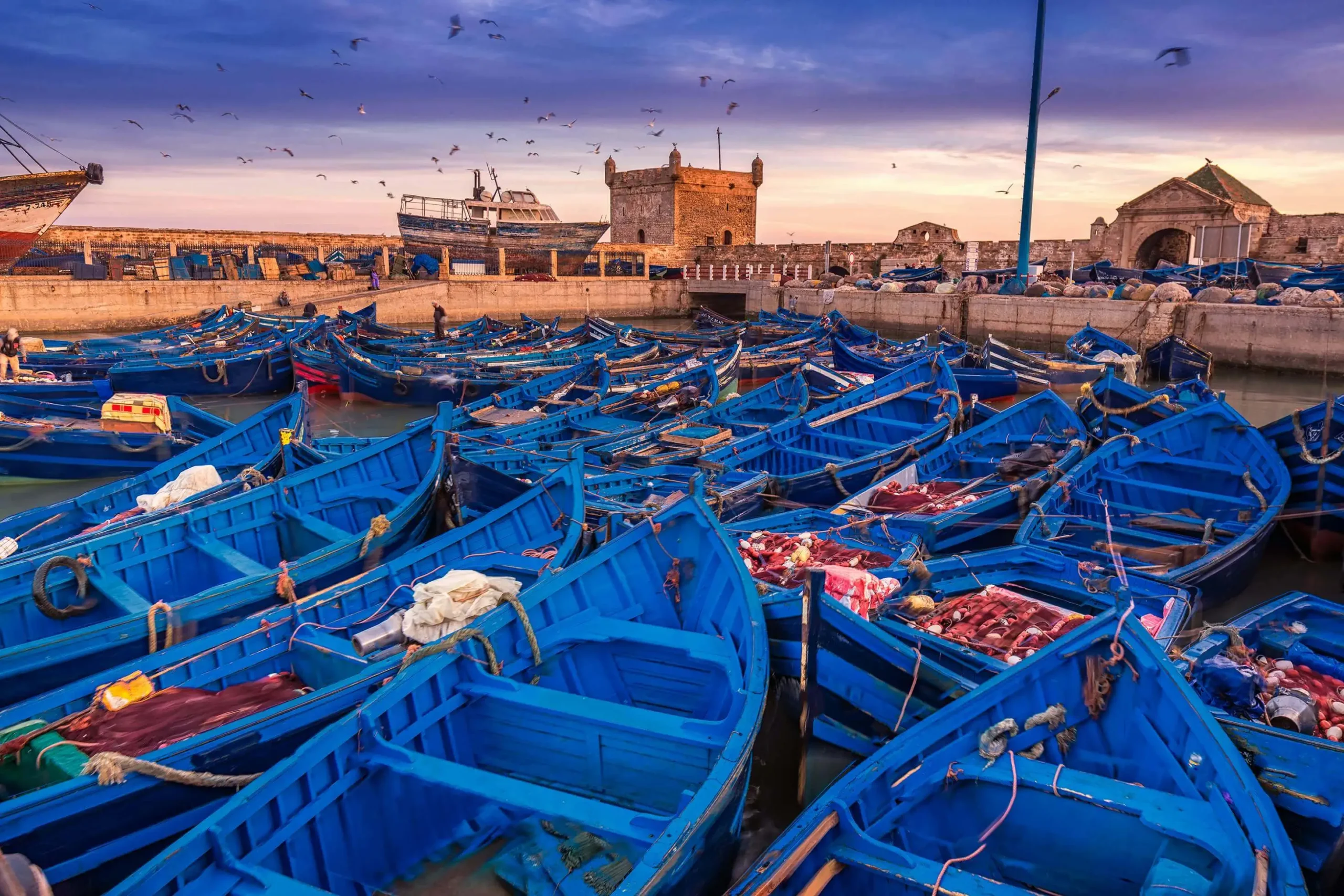 56e4a8e265a1f7a3a246b85bcf88d672-essaouira Peaceful summer scene with boats gently floating on a calm sea under a clear sky, evoking the tranquility and softness of the season.
